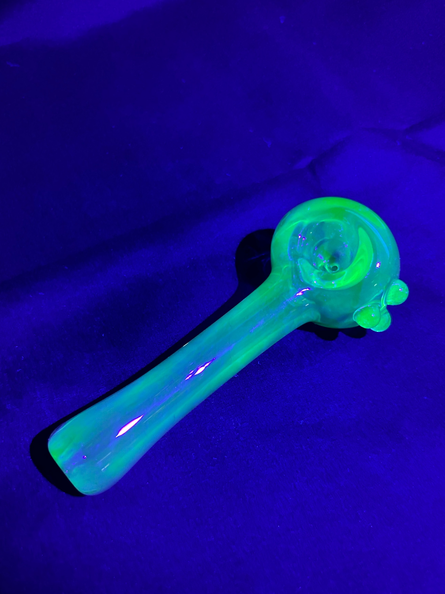 Glowing green glass pipe on a dark background